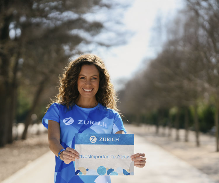 Laura Madrueño con camiseta Zurich mostrando un dorsal con el # Nos Importan Tus Metas